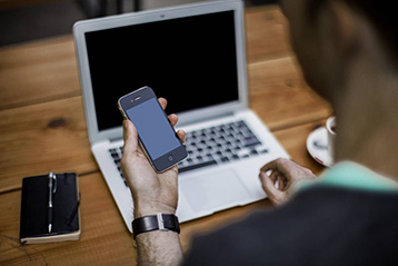 Man using a laptop and a smartphone